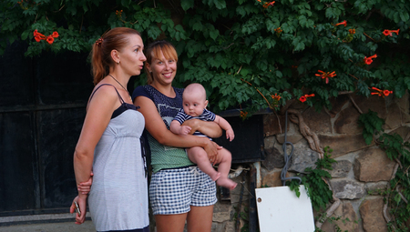 Two mothers and baby boys standing near pomegranate tree. Summertime.の写真素材