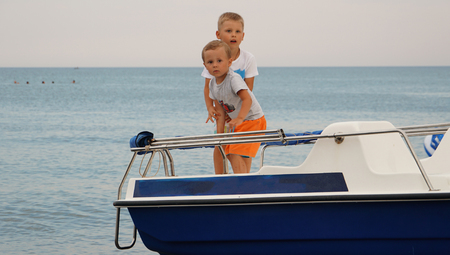 Two cute boys on the boat in the sea. Summer vacation on the sea beach.の写真素材
