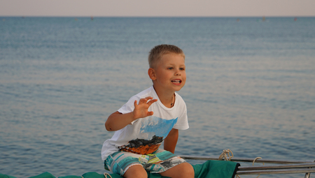 Young happy boy on board of the sea motorboat with welcome handの写真素材