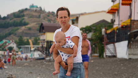 Portrait of the woman with cute baby in mothers hands on the beachの写真素材
