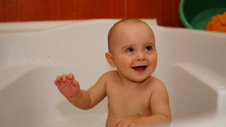 Funny laughing little child smiling and playing with water in a bathroom. Toddlers bathes.の写真素材