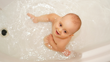 Funny little child smiling and playing with water and foam in a bathroom. Toddlers bathes.の写真素材