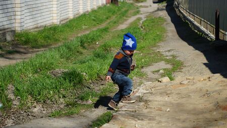 Little boy with hat walking by the dirt road outdoorsの写真素材