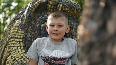 Close up portrait of caucasian teen boy. Funny cute teenager in summer park at day. Child smiling with grin and looking at camera .の写真素材