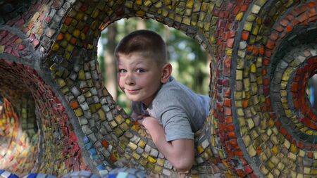 Close up portrait of caucasian teen boy. Funny cute teenager in summer park at day. Child holding his chin looking at camera through a hole .の写真素材