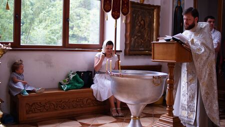The sacrament of baptism. Orthodoxal Christening the baby. Child, priest and godfather.