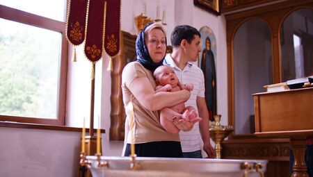 Rite of the baptism of the little boy in the arms of godmother in the Christian traditionの写真素材