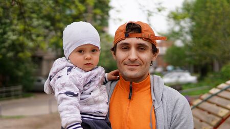 Handsome adult father holding cute little baby on his arms, smiling from tenderness and love.の写真素材