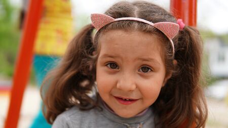 Portrait of happy smiling child girl with a horns on the head playing at playground in the Summerの写真素材