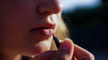 Young woman draw lips with red pencil. Close-up shotの写真素材