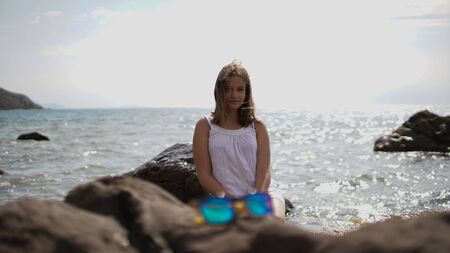 Beautiful girl with blur glasses in front posing at the camera on the sea backgroundの写真素材