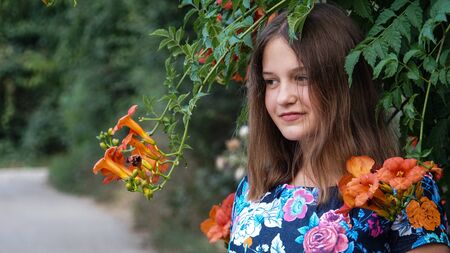 Beautiful girl posing at the camera among branches with orange flowers.の写真素材