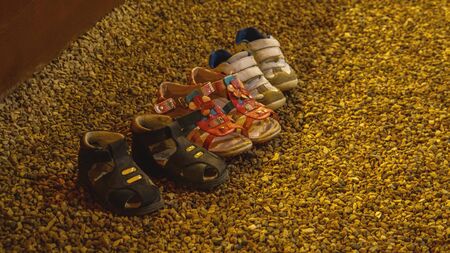 A different children's shoes abandoned on a pebble beachの写真素材