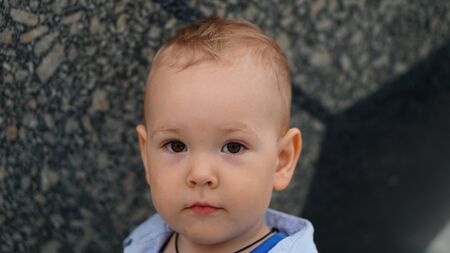 Portrait of the handsome cute boy stands outdoor near ball sculpture