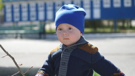 Cute little boy portrait in a blue hat on the street in cityの写真素材