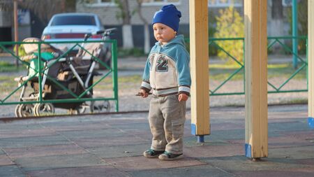 Cute little boy portrait in a blue hat on the playground in city