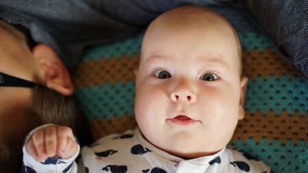 Looking funny cute baby on the couch. The child looks at the camera with interest.の写真素材