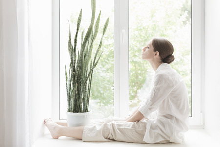 Woman sitting on a windowsillの写真素材