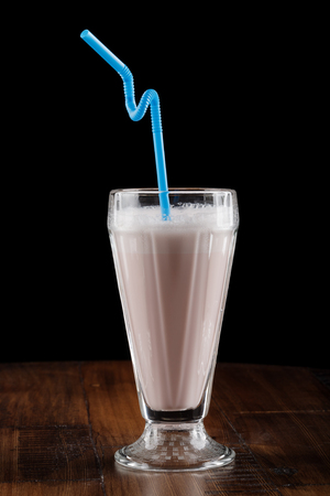 Milk shake (cocktail) with berry in glass on brown wooden tableの写真素材
