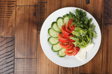 vegetable mix (salad, cucumber, tomato, parsley) and chees on a white plate.の写真素材