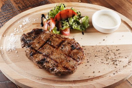 strip-loin steak with sauce on wooden surface.の写真素材