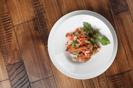 Achichuk - traditional uzbek salad with tomatoes, onions and greens in white plate.の写真素材