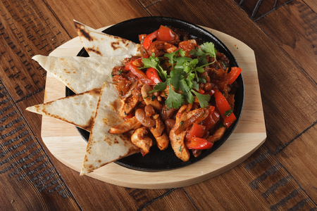 Fajitas with chicken and bell pepper in a pan. Wooden background.の写真素材