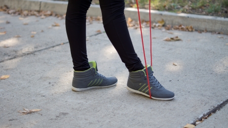 Cropped view image of the feet of a woman wearing trainers with a red skipping ropeの写真素材