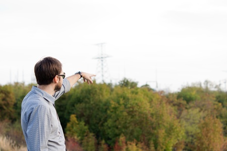 Rear view of a man pointing over open countryside with bush and copy space