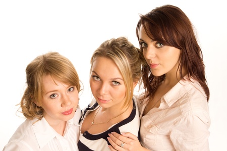 Three attractive young teenage woman standing close together in a descending row looking at the camera isolated on whiteの写真素材