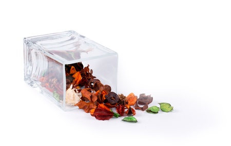 Fragrant natural potpourri with dried flowers, leaves and spices spilling out of a rectangular glass container onto a white background for that special fragrance in the houseの写真素材