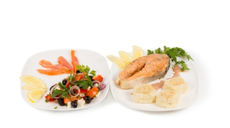 Cooked salmon steak and salad served on two seperate platesの写真素材