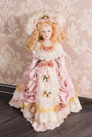 Pretty delicate antique doll with long blonde ringlets dressed in a beautiful pink nineteenth century gown and accessoriesの写真素材