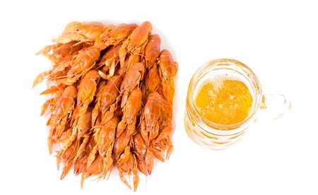 Seafood meal of gourmet cooked whole unshelled prawns stacked tightly on a platter and served with a pint of beer, overhead view on whiteの写真素材