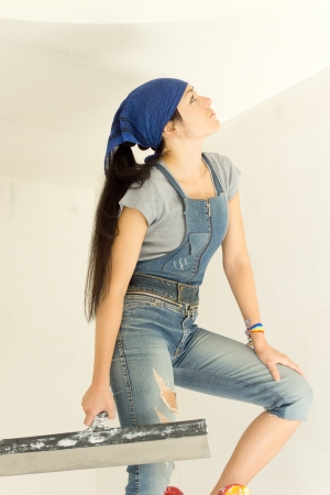 Woman applying wallpaper looking at her work standing on a stepladder or trestle while making sure the paper is evenの写真素材