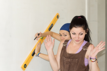 Woman throwing up her hands in defeat while working on a DIY renovation project with a female friendの写真素材
