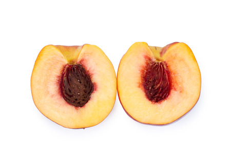 Overhead view of the two halves of a halved juicy ripe nectarine showing the texture of the flesh and pip, isolated on whiteの写真素材
