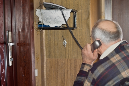 Elderly man talking on a telephone sitting with his back to the camera holding the handset to his earの写真素材