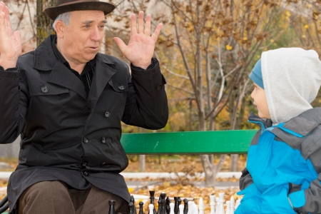 Cute little boy confronting his grandfather who is playfully protesting his innocence with his hands...