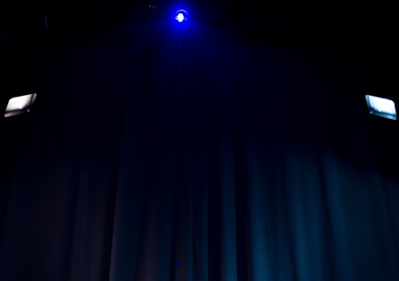 Spotlights shining in the darkness in an empty entertainment venue or nightclub against a curtained backdropの写真素材