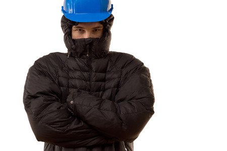 Pugnacious young thug in a black balaclava and hardhat standing blocking the way with an angry...