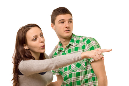 Young woman pointing excitedly with her hand and exclaiming in surprise as she draws the attention of her boyfriend to something to the right of the screen, isolated on whiteの写真素材