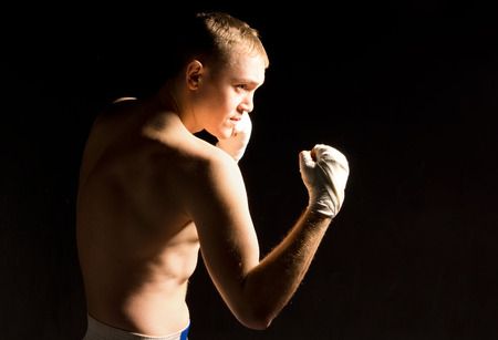 Young boxer squaring off during training raising his fists while closely watching his opponent for a...
