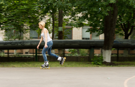 Fit middle-aged woman with long blond hair out roller skating on roller blades enjoying the exercise as she speeds along the tarmacの写真素材