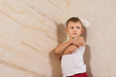 Serious Little White Kid Wearing Undershirt Isolated on Wooden Wallsの写真素材