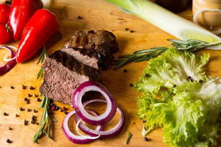 Close up Tasty Grilled Meat Slices on Wooden Chopping Board with Spices on Sides.の写真素材