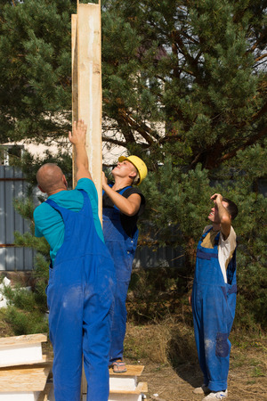 Group of construction workers aligning a prefab wooden wall panel on a new build houseの写真素材