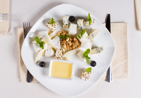 Overhead view of a plate of bite sized gourmet appetizers with cashew nuts and a creamy savory dipping sauce served at tableの写真素材