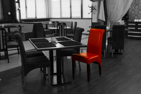 Single red chair in a greyscale nightclub interior with selective color showing modern tables and chairsの写真素材
