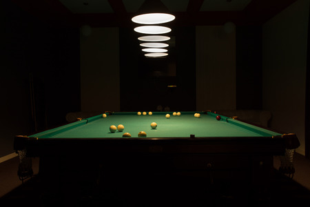 Billiard Balls Scattered on Pool Table in Empty Dimly Lit Pool Hall